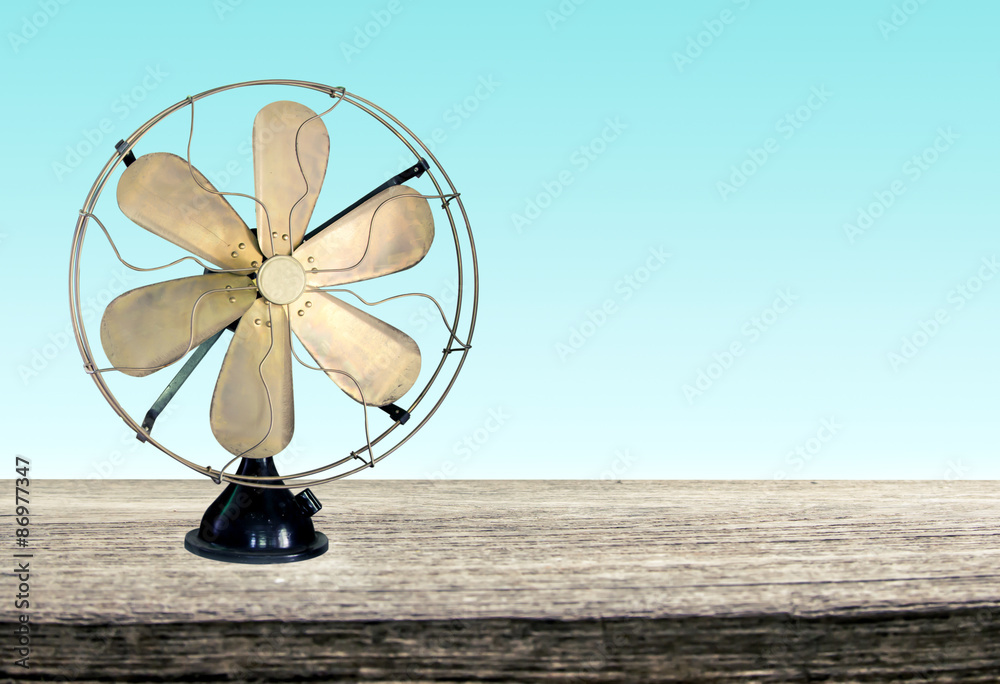 vintage metal fan on wooden table front green background