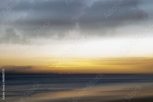 long exposure photo with the camera panned from left to right to make a blurry sunset beach scene
