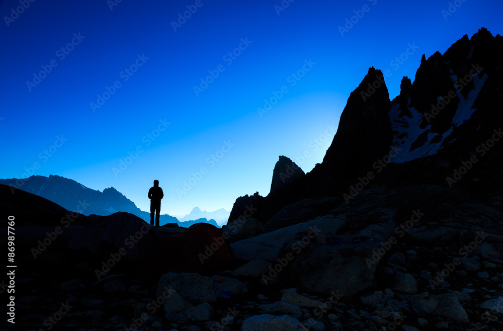 Silhouette of a person looking at the mountains just before sunrise.
