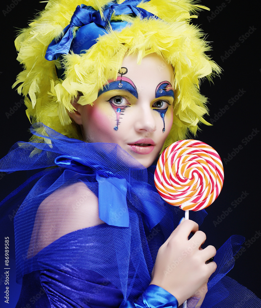 Girl with with creative make-up holds lollipop