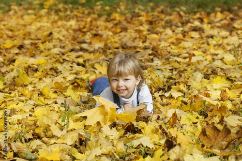 happy boy in leaves of autumn lies