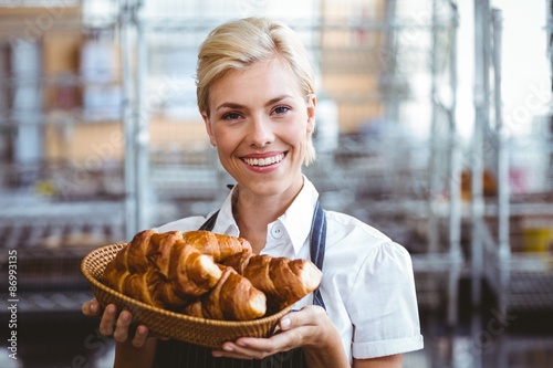 Cheerful gorgeous waitress holding a basket with croissant