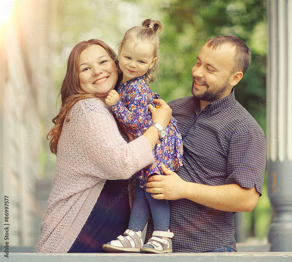 Fototapeta premium Mom and young daughter and dad, a young family on a walk in the park in summer