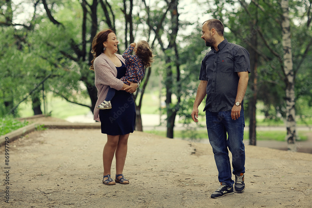 Obraz premium Mom and young daughter and dad, a young family on a walk in the park in summer