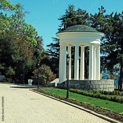White classical rotunda in summer ornamental garden