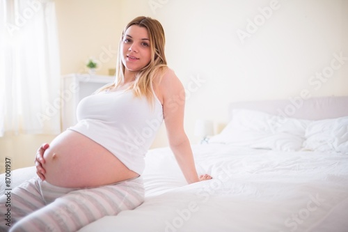 Pregnant woman sitting on bed 