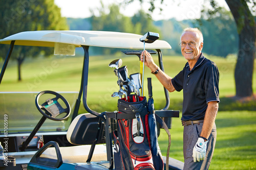 Mature man with a golfcart on the green