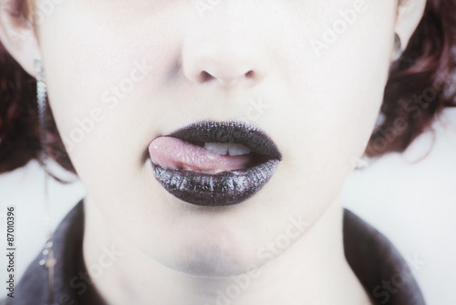 Closeup of a woman wearing black lipstick and licking her lip