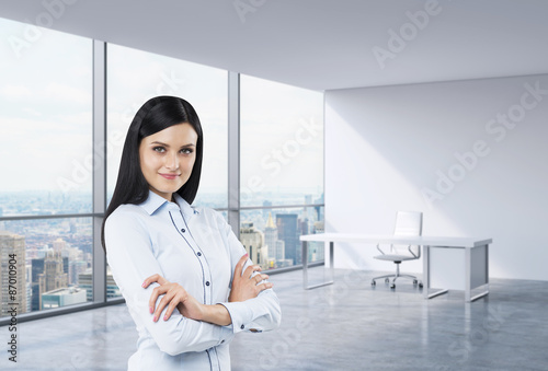 A brunette business woman in a workplace at modern corner panoramic office in New York, Manhattan. A concept of financial consulting services. © ImageFlow