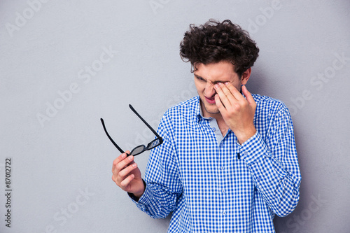 Man holding sunglasses and rubbing his eyes