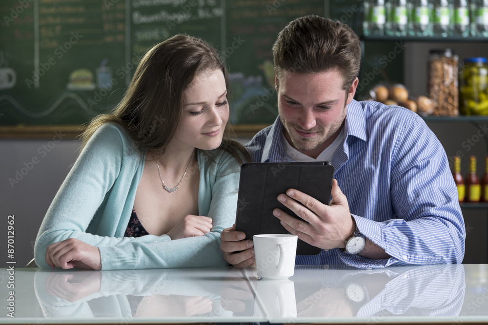 A young couple using a tablet/ipad in a cafe A young couple using a tablet/ipad in a cafe