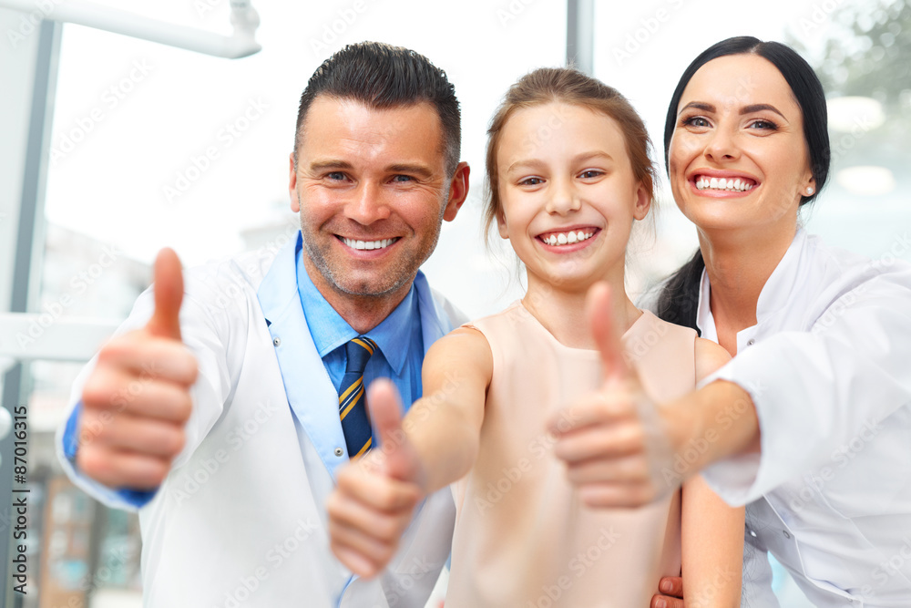 Dentist doctor, assistant and little girl all smiling at camera Dentist doctor, assistant and little girl all smiling at camera