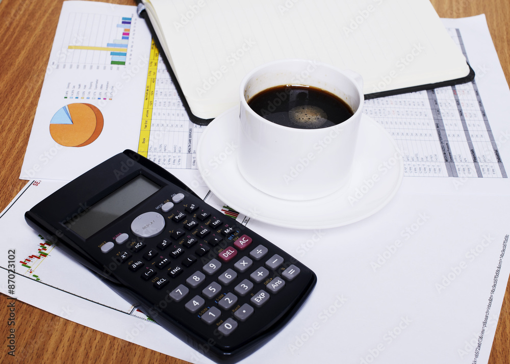 Coffee cup and calculator with blank book page on worktable with Coffee cup and calculator with blank book page on worktable with