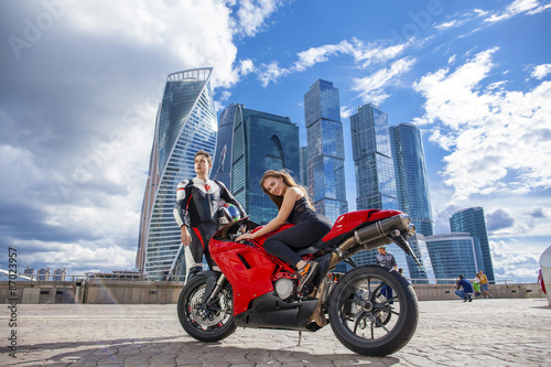 Young couple on a sports bike on the background of the city skyl