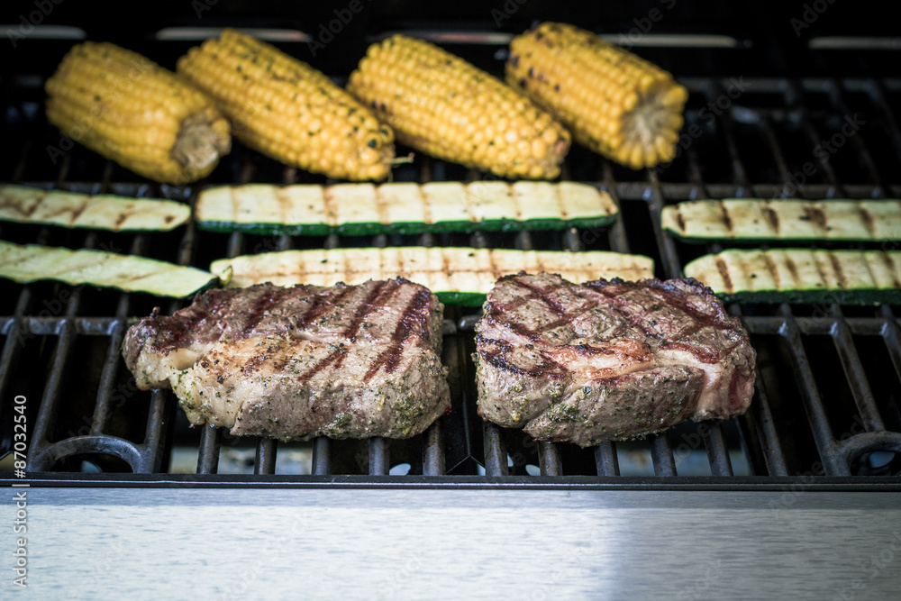 Rib eye steak with zucchini and corn on grill