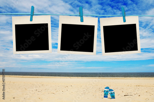 blank instant photos hanging on clothesline at the beach