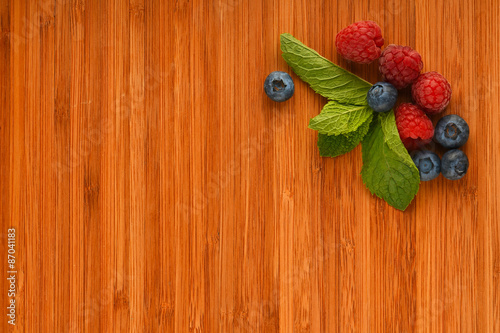 Cutting board with blueberries, raspberries and mint leaves
