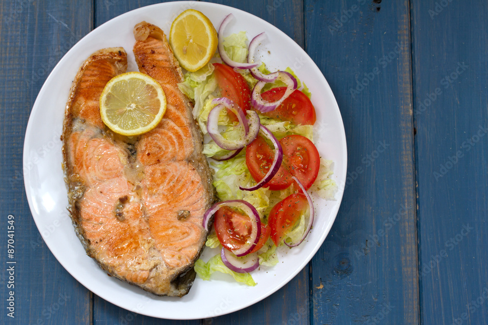 fried salmon with vegetable salad and lemon on white plate fried salmon with vegetable salad and lemon on white plate