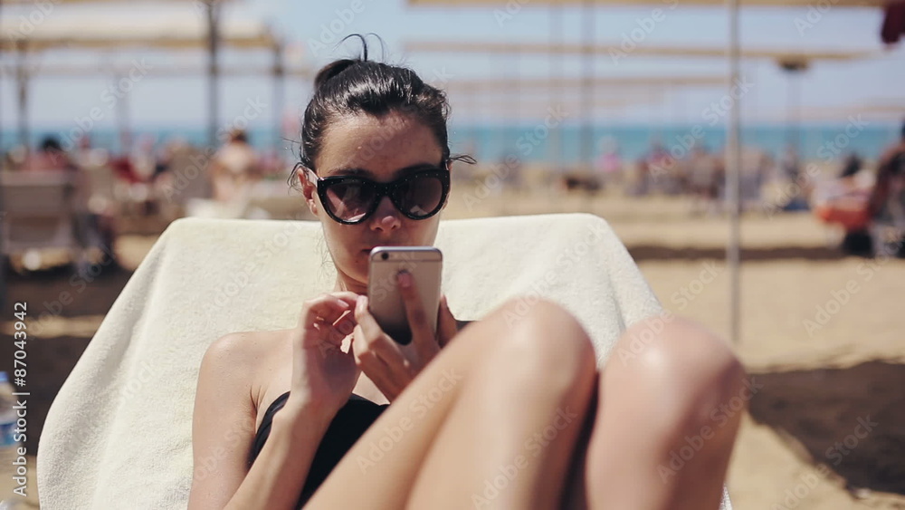 Attractive woman in sunglasses relaxing and using app on smartphone