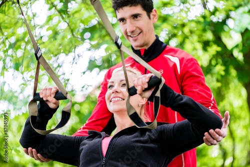 Sportliches Paar trainiert am Sling Trainer für Fitness photo