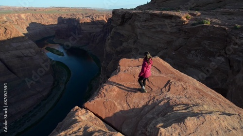 Girl hiker walking towards the edge of Horseshoe Bend Page arizona looking down at Colorado River