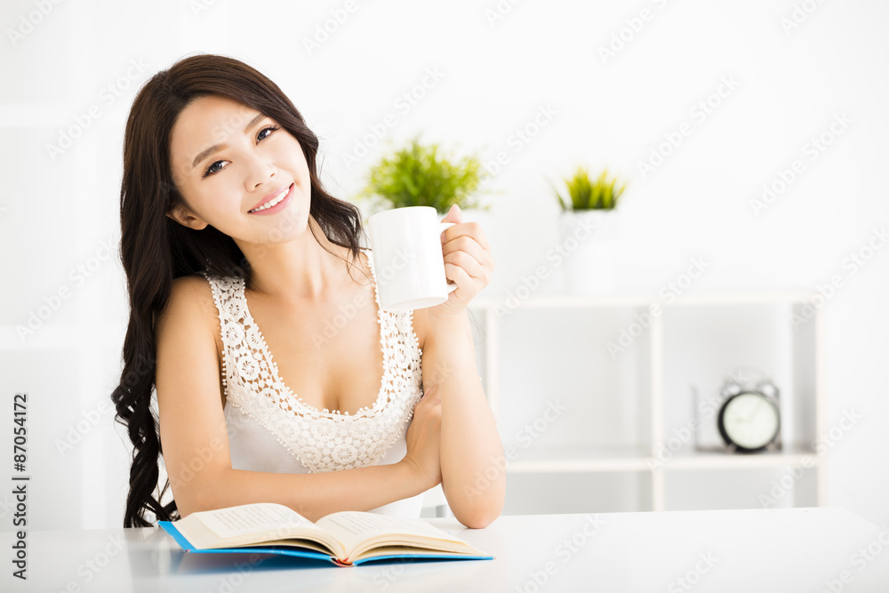 Happy young woman reading book in living room Happy young woman reading book in living room