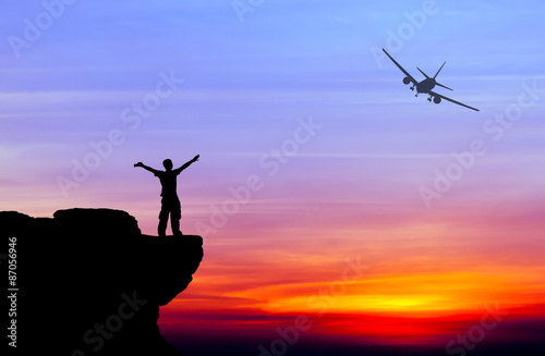 Silhouette of a man on the rock and silhouette commercial plane