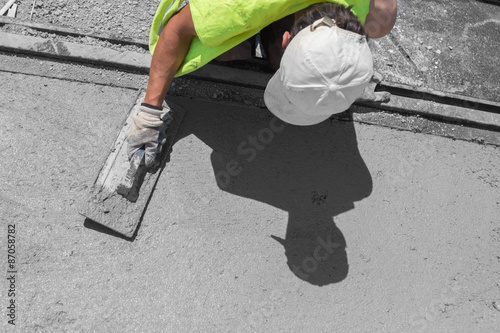 Construction worker leveling concrete pavement.