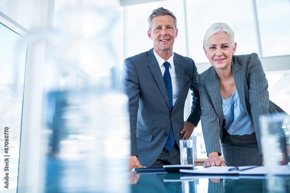 Business people looking at camera behind desk Business people looking at camera behind desk