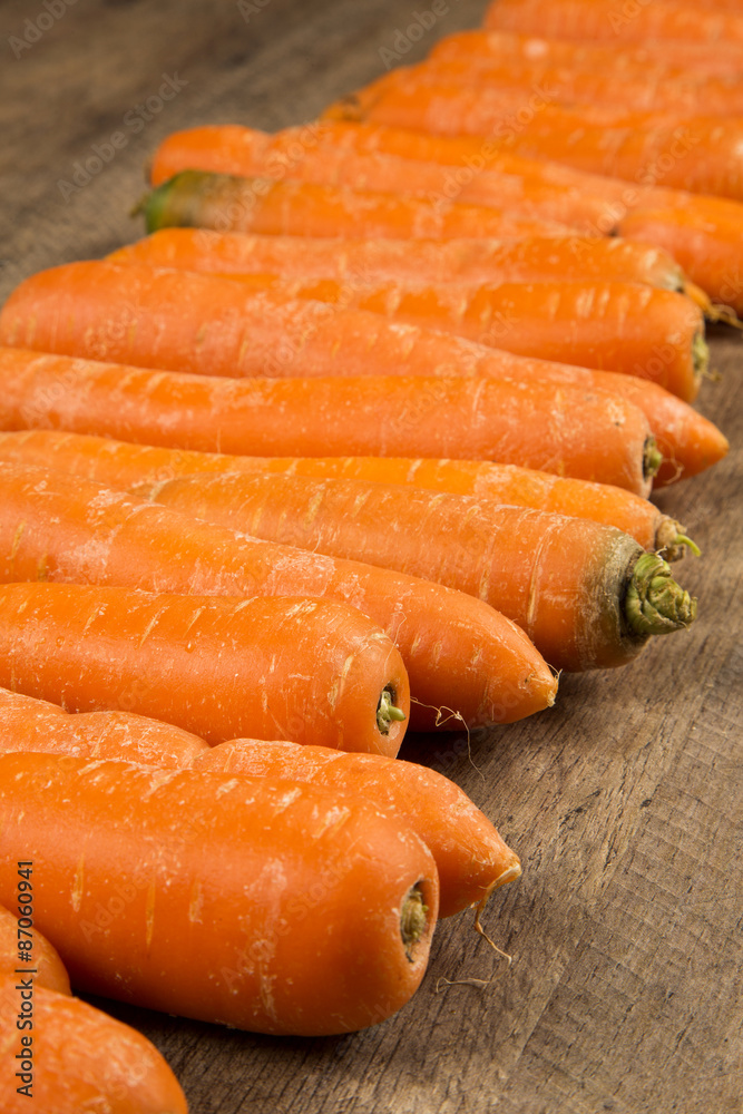 Fresh carrot with green leaves on wooden table Fresh carrot with green leaves on wooden table
