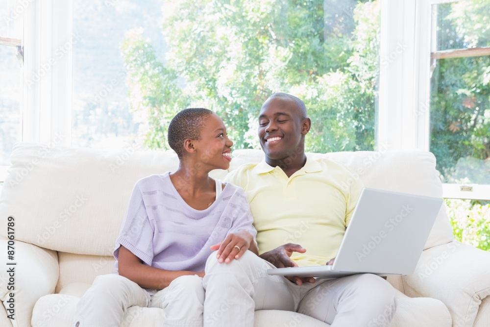 Happy smiling couple using laptop on couch Happy smiling couple using laptop on couch