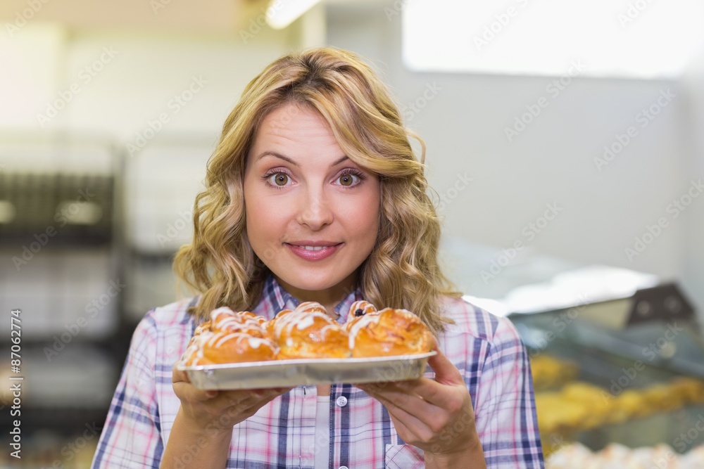 Portrait of a smiling blonde woman showing a pastry Portrait of a smiling blonde woman showing a pastry