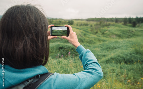 Hiker woman photographs the summer landscape