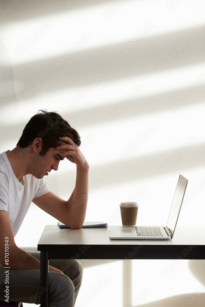 Stressed Male College Student Using Computer In Classroom
