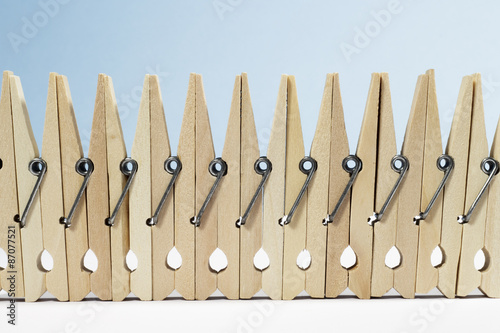 A "fence" formed by spring-type wooden clothespins on white floor and blue background