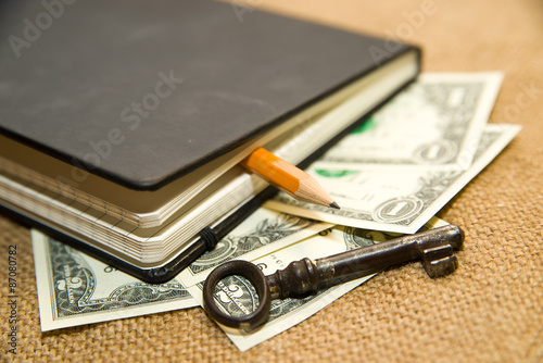 notebook, key, pencil and money on the old tissue