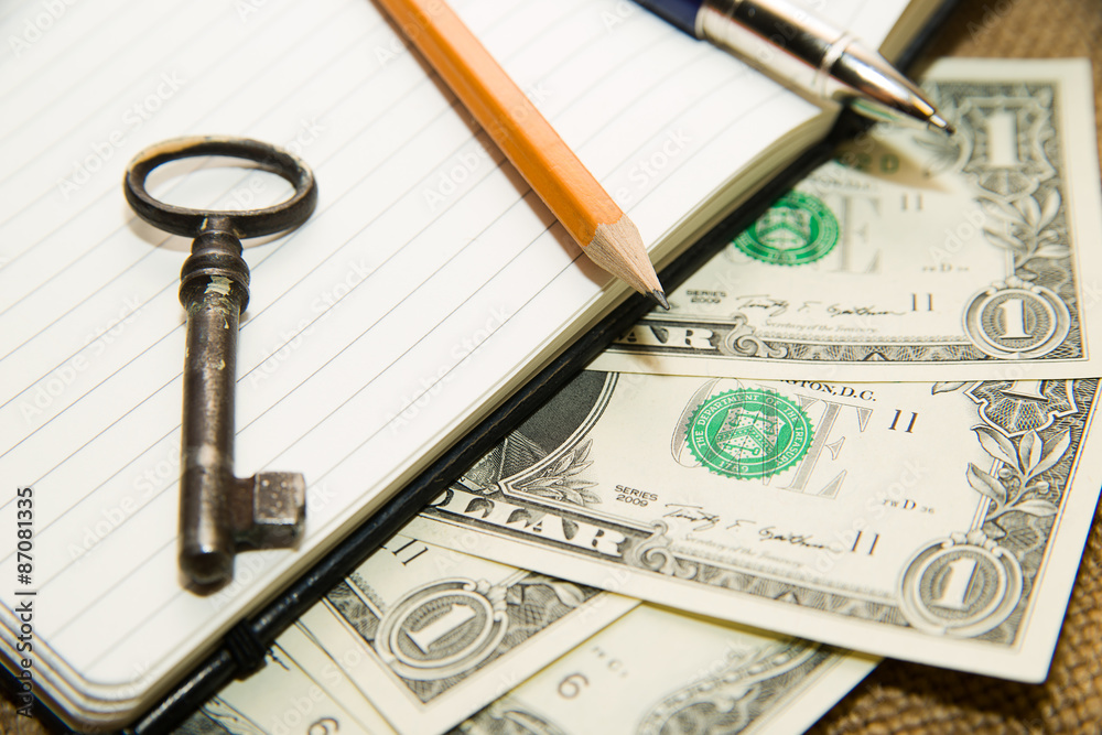 Opened notebook, pencil, pen, key and money on the old tissue Opened notebook, pencil, pen, key and money on the old tissue