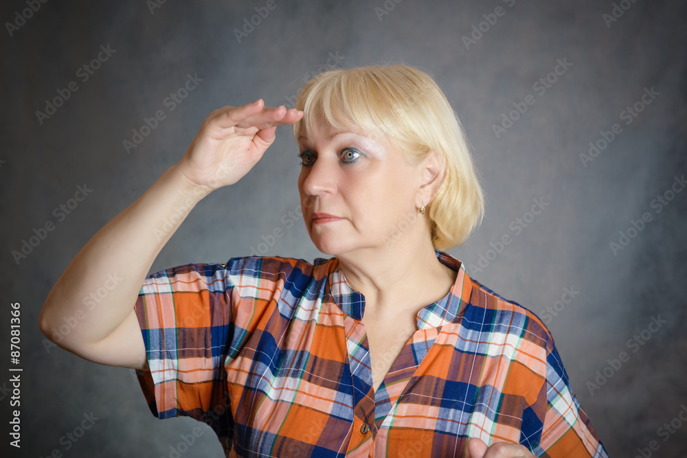 Fototapeta premium Middle aged woman looking far, holding her arm hear her eyes.