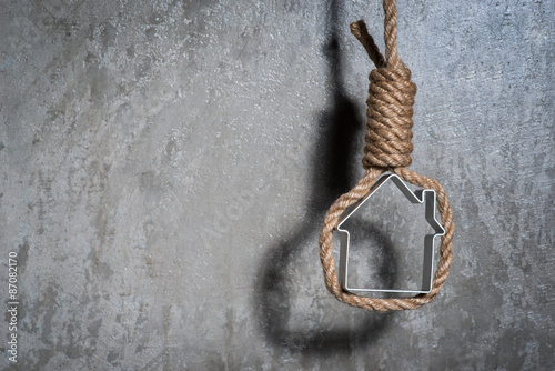 Small house framed with hangman's noose over the grey concrete wall