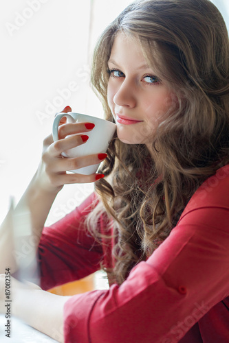 A woman in a restaurant is drinking coffee photo