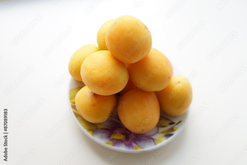 Спелые абрикосы на маленьком фарфоровом блюдце