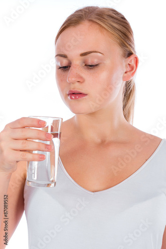 Portrait of a young happy girl holding a glass of water after fitness  isolated on a white background