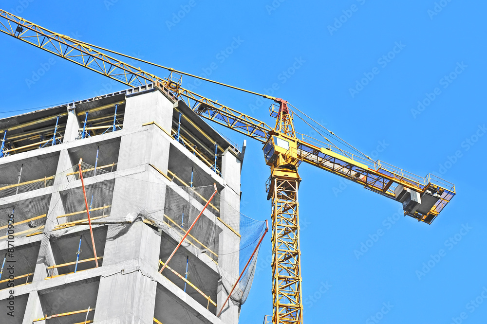 Fototapeta premium Crane and building construction site against blue sky