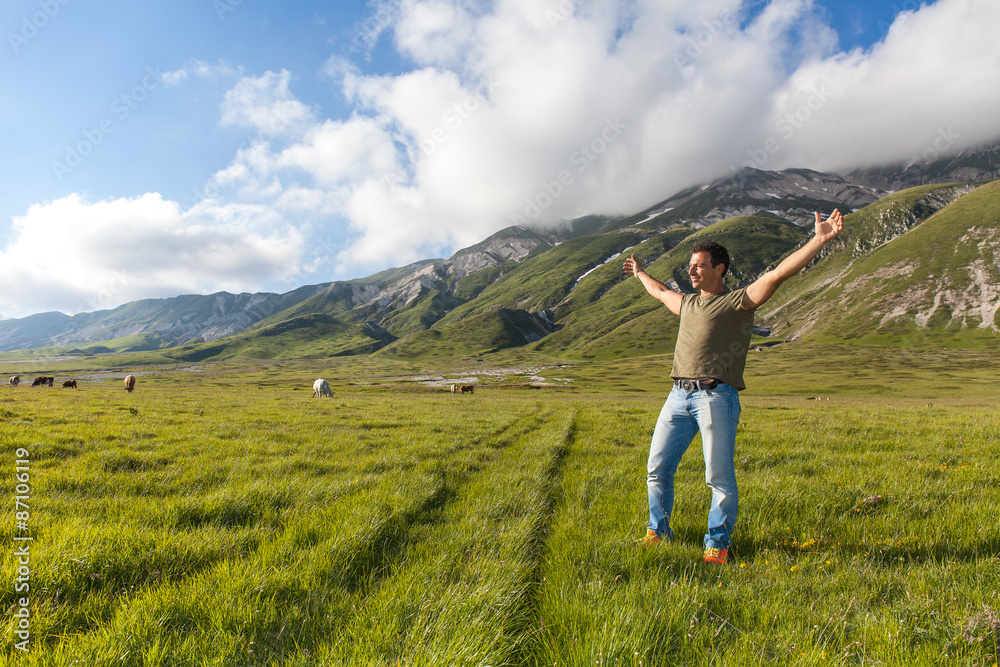 Uomo felice a braccia aperte alzate verso il cielo in un altipiano montano