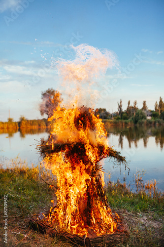 Tablou pe pânză Burning an effigy of straw in the day, Midsummer on the lake