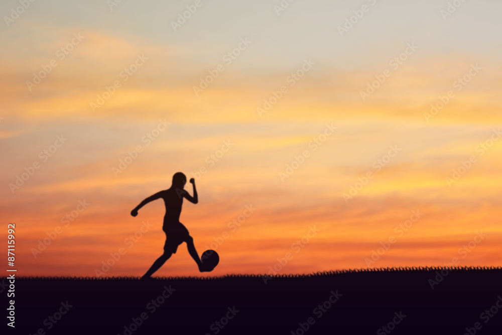 Silhouette of children playing soccer background sunset.