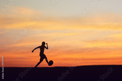 Fototapeta Naklejka Na Ścianę i Meble -  Silhouette of children playing soccer background sunset.