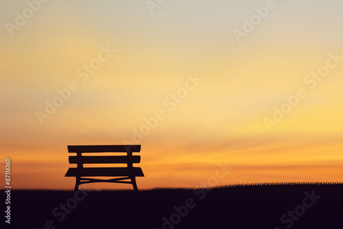 Silhouette chair on the grass Sunset background