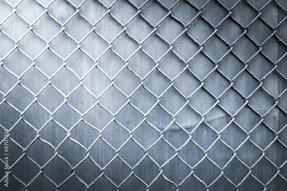 steel wire mesh fence wall background with light from corner Stock