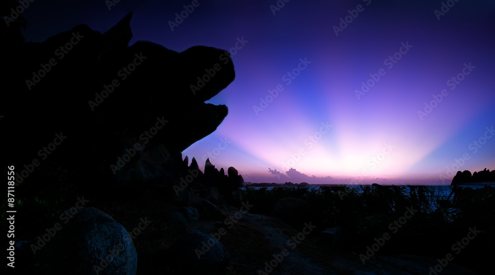 Naklejka premium Ray sunrise side of the dog's head rock with purple halo rhyme from horizon as dawn great moments. Photo taken at Ke Ga lighthouse, Binh Thuan.